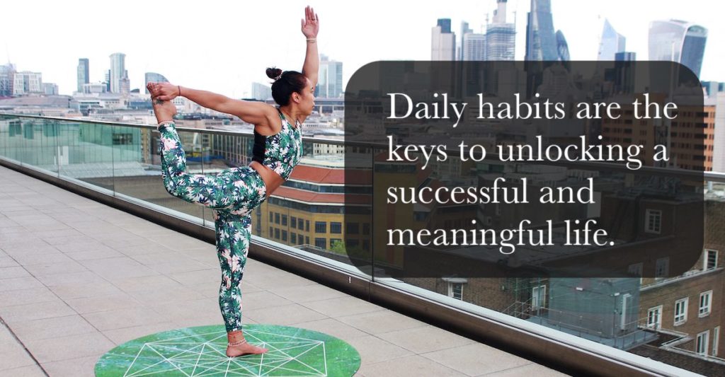 A lady in performing yoga on a roof of a building outline in a city scape. A caption reads, Daily habits are the keys to unlocking a successful and meaningful life.