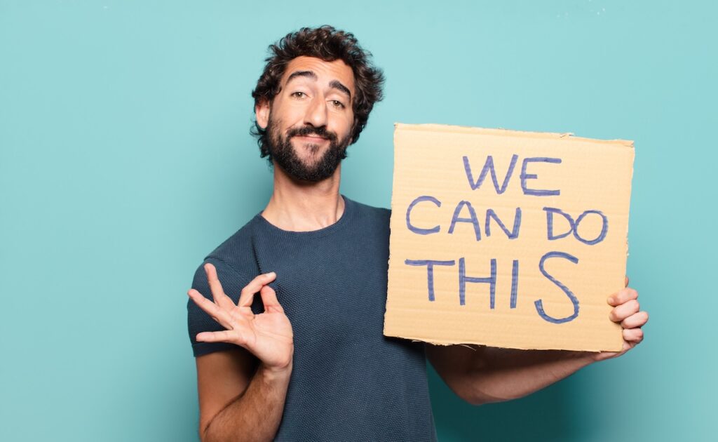 Man holding a sign saying 'We Can Do This', symbolizing tips for staying motivated.