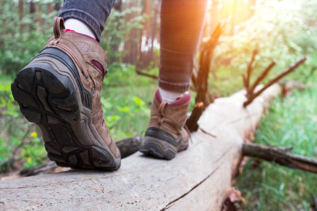 Close-up of hiker's boots on a forest trail, symbolizing the physical and mental benefits of hiking.