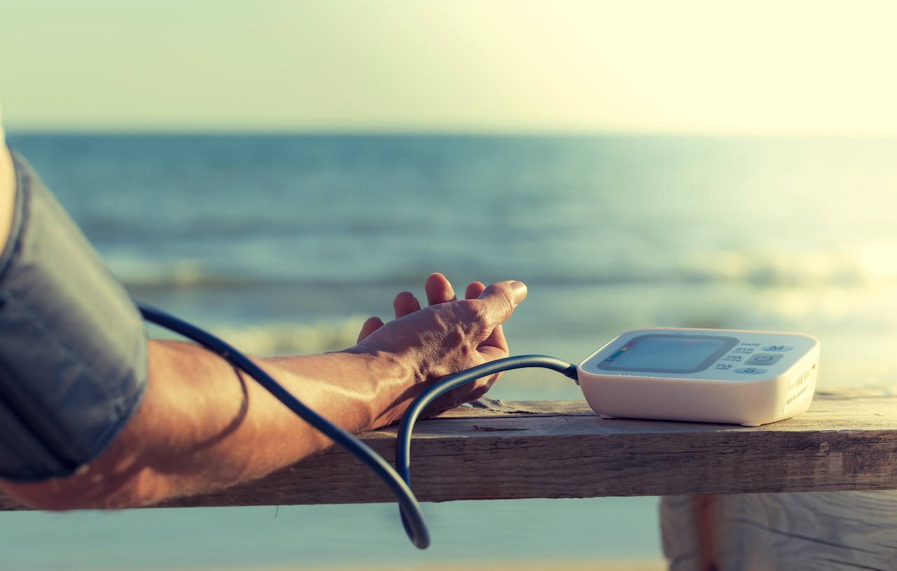 A person measures their blood pressure by the sea, highlighting the importance of tracking cardiovascular response to exercise.