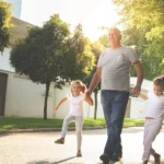 An older gentleman taking a leisurely walk with his two young granddaughters, working on lowering cholesterol by exercise.